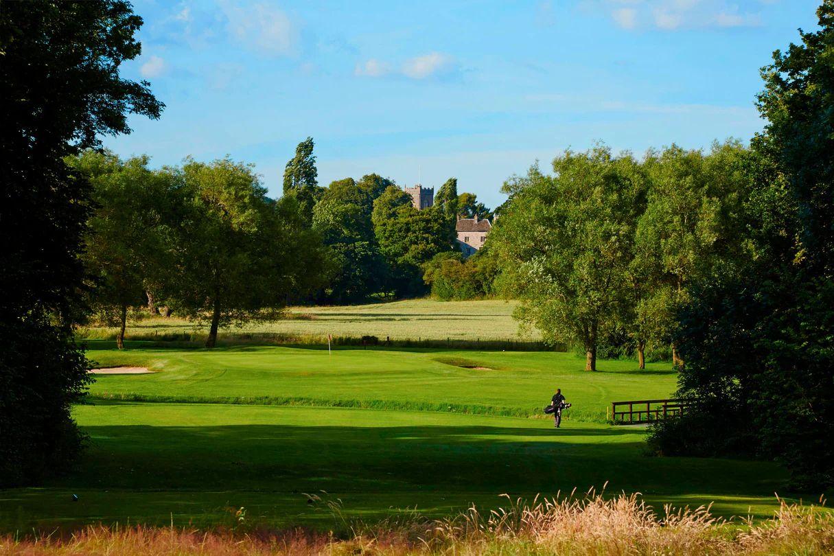 A golf green lies beside the historic manor house and modern hotel wing.