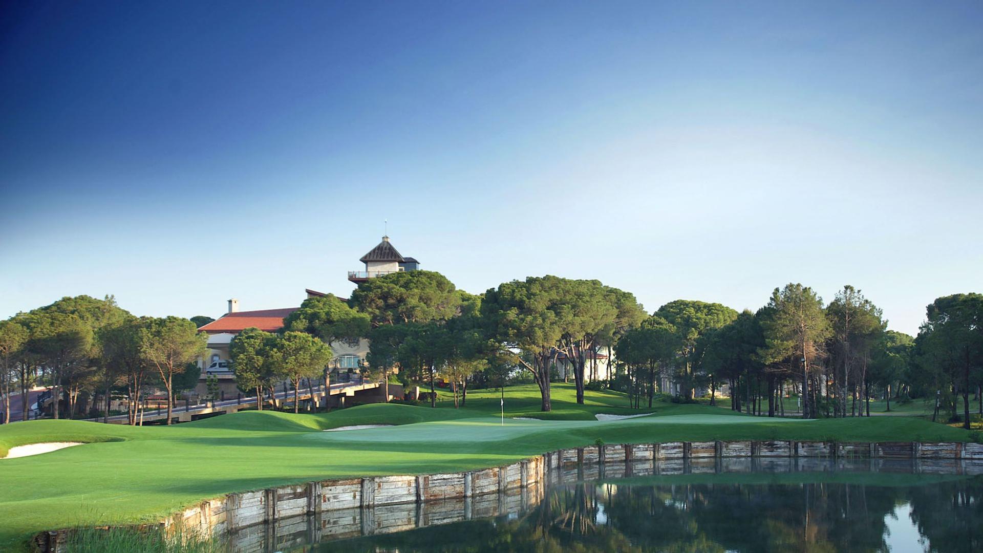 Green on the Montgomerie Maxx Royal Course with a water hazard in front and the clubhouse behind