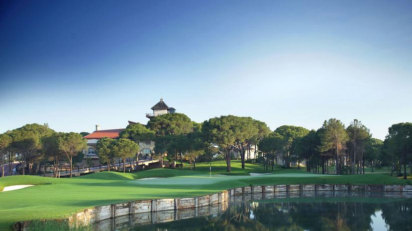 Green on the Montgomerie Maxx Royal Course with a water hazard in front and the clubhouse behind