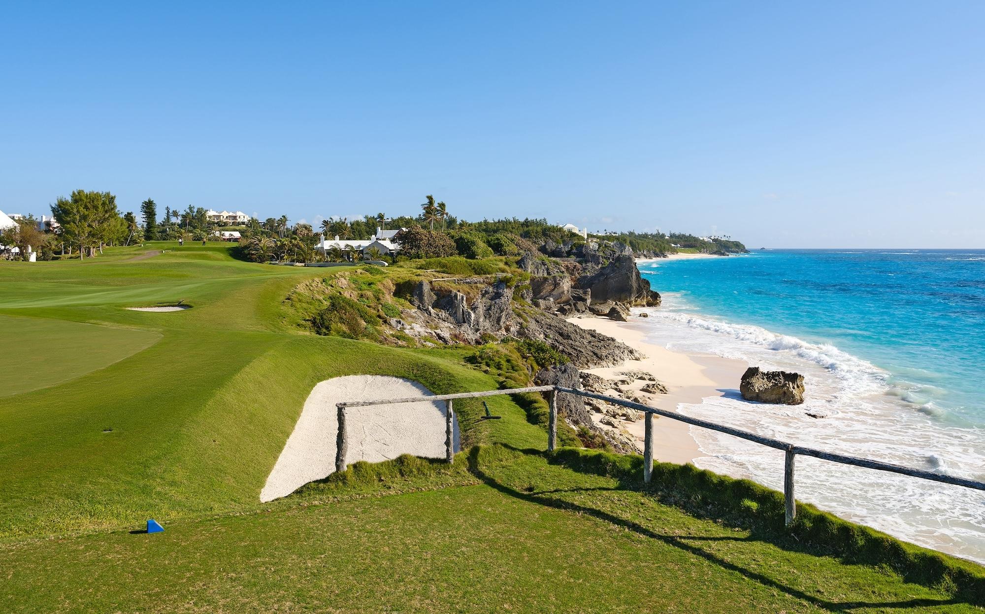 A close-up view of the golf course with a sand bunker overlooking the ocean and rocky shoreline.