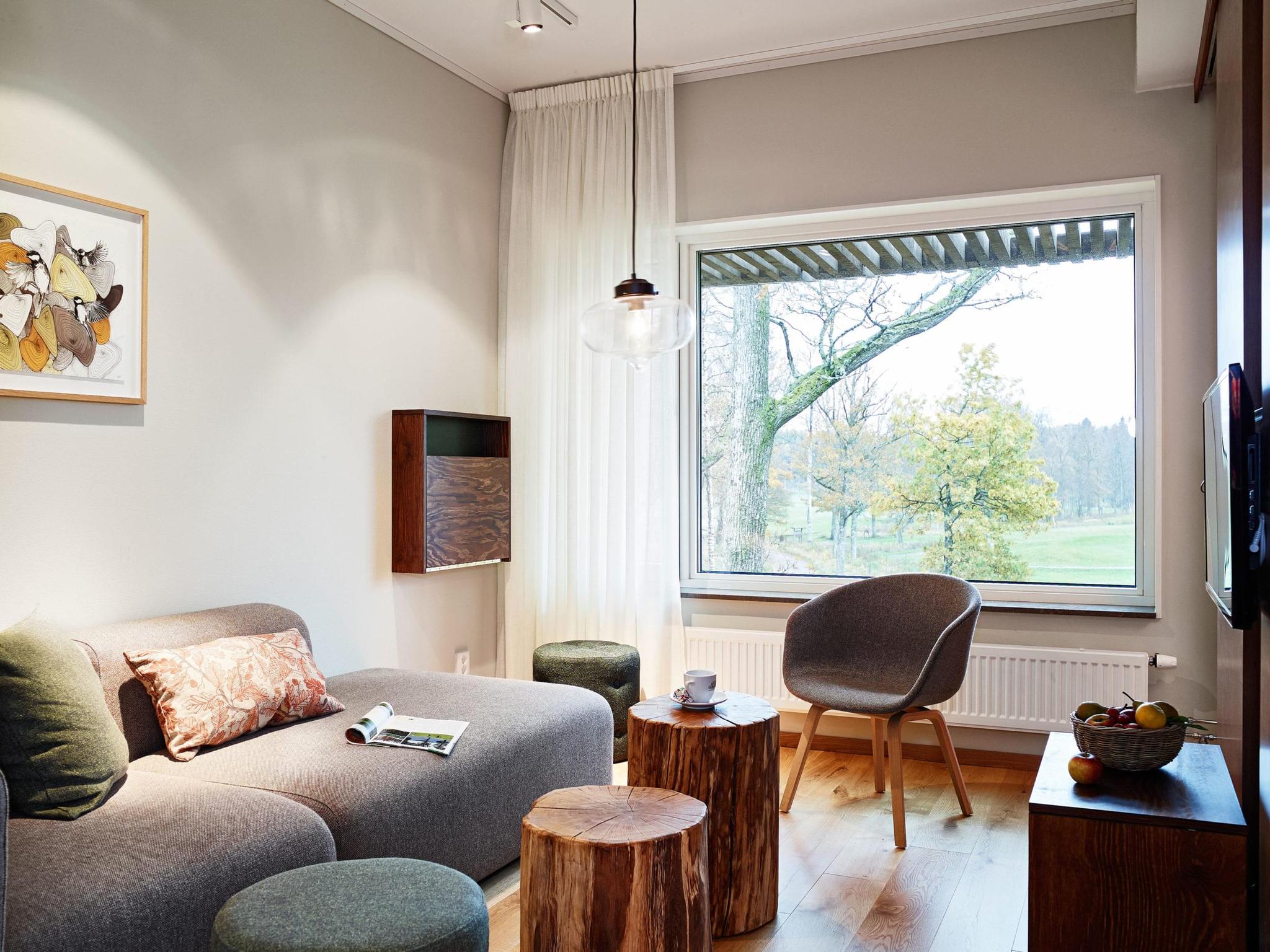 A cozy modern lounge with a large window view of trees and a golf course.