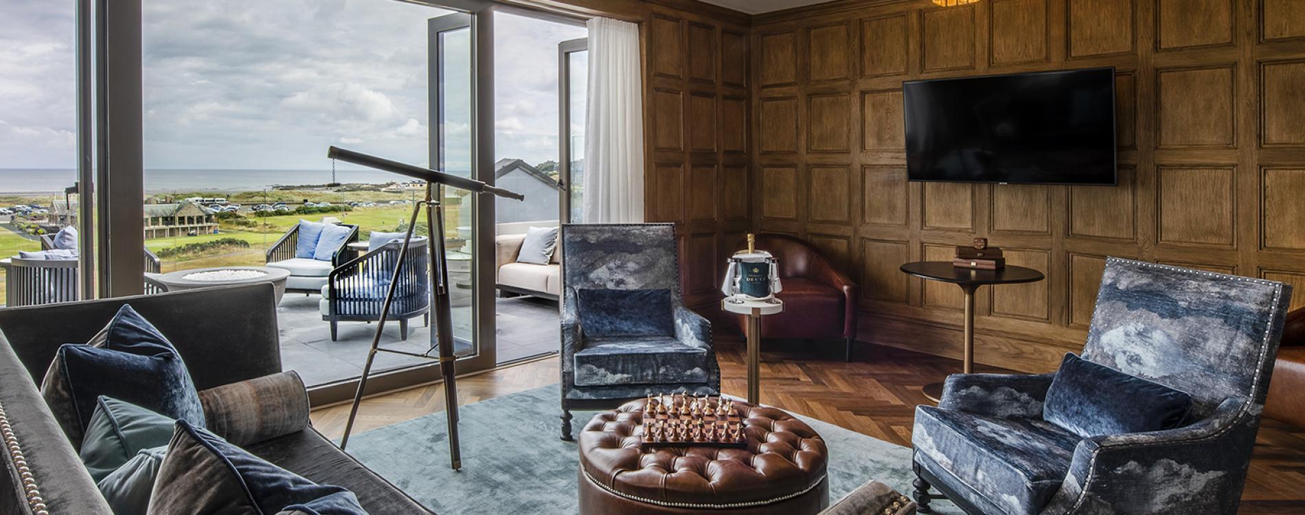 A stylish lounge with a balcony showcasing sweeping golf course and sea views.