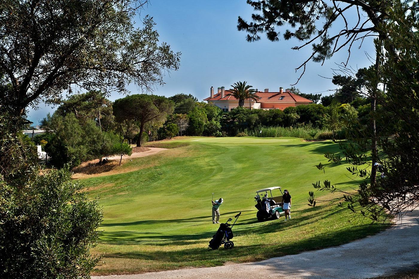 Two players playing an up hill approach shot to the green