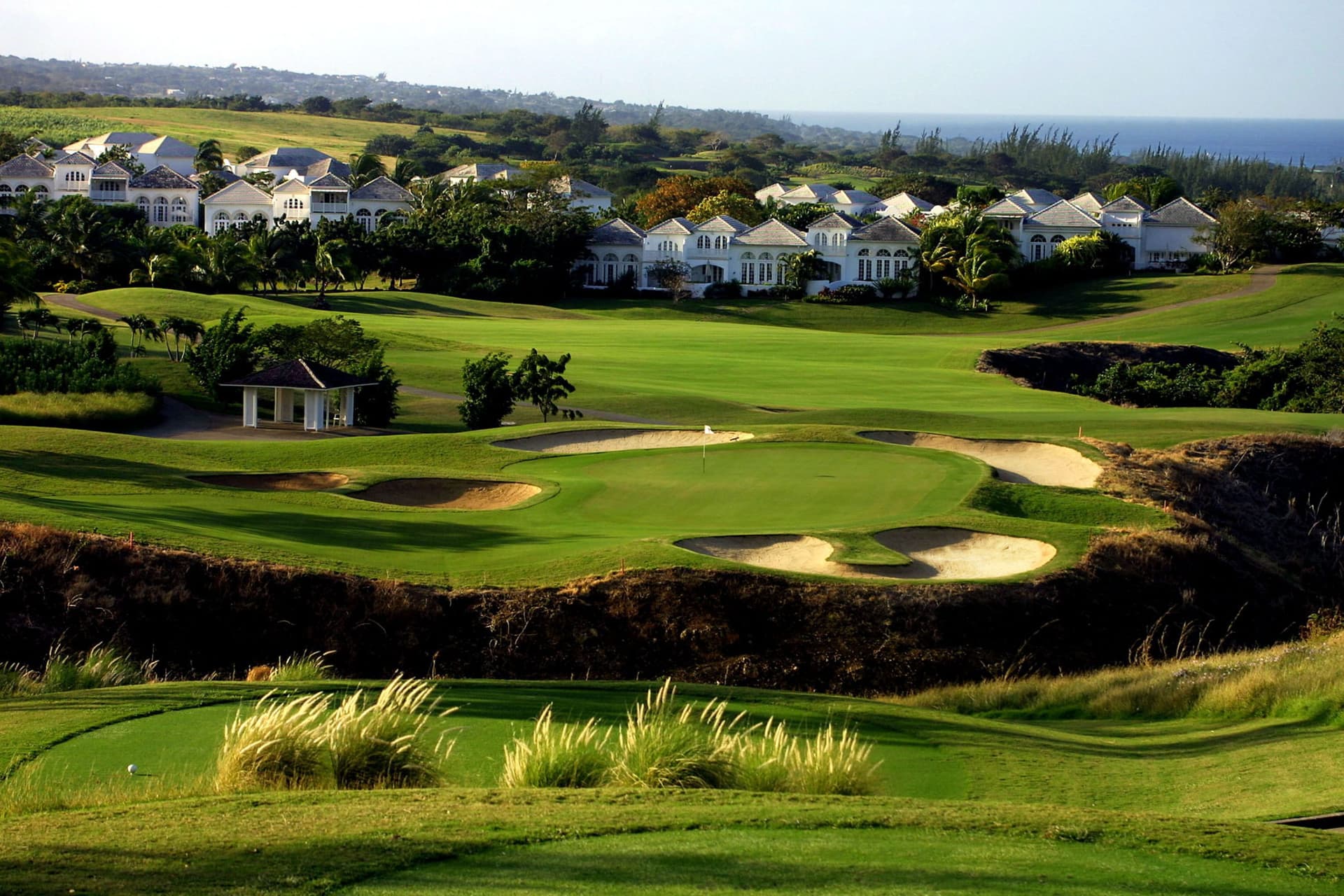 Elegant villas overlook a lush green course with challenging bunkers.