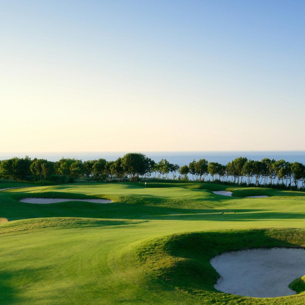 Beautiful seaside golf course with scattered bunkers and ocean backdrop.
