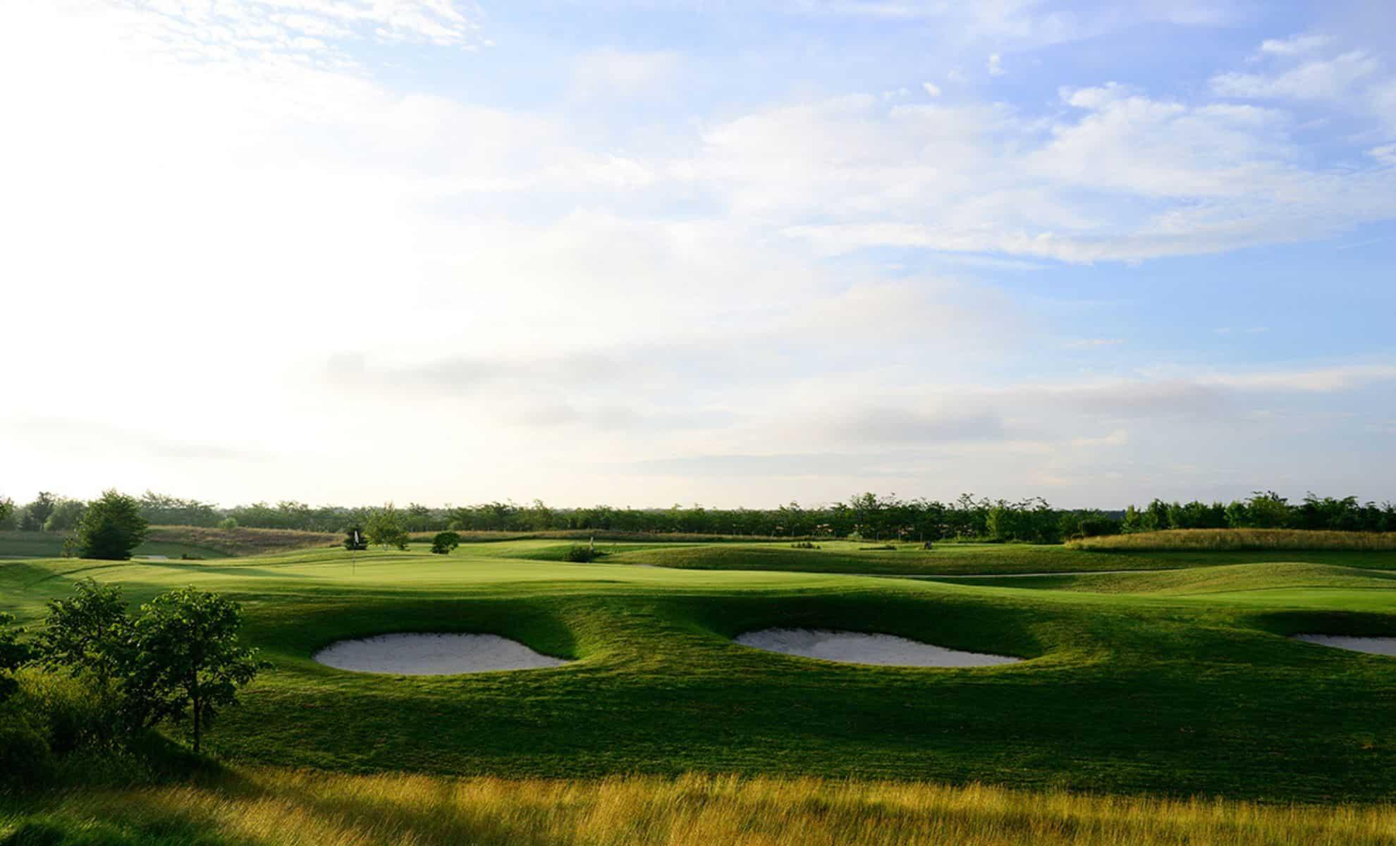 Rolling greens with deep sand bunkers under a bright sky.