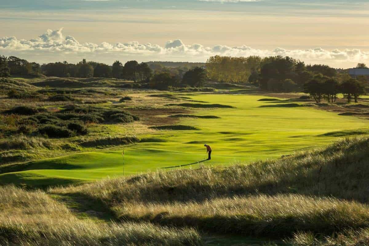 Golfer putting on smooth green at the Southport & Ainsdale Golf course on a sunny evening.