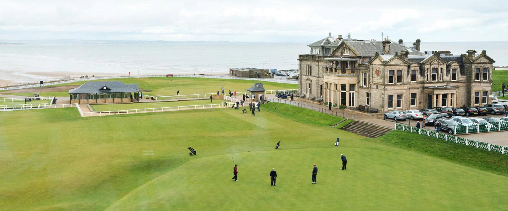 Golfers enjoying their round of golf at the st andrews links course with the clubhouse looking over them