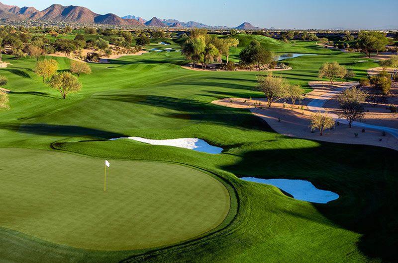 A lush golf course with rolling fairways and scenic mountains in the distance.