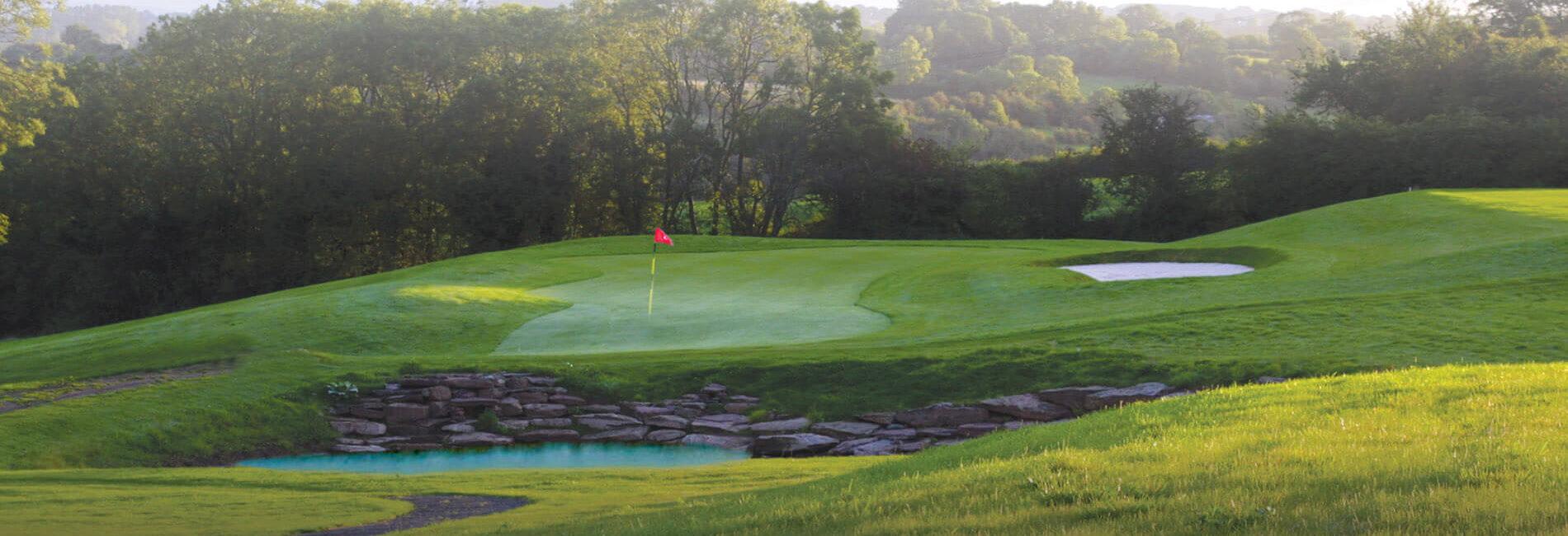 Elevated green placed next to a water hazard with a stone barrier