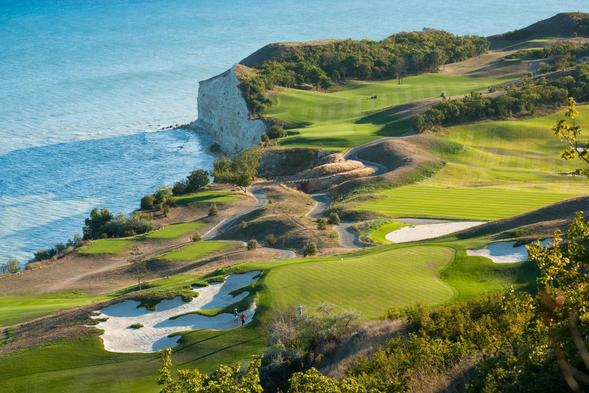 Aerial view of golfers enjoying their round on a green surrounded by large sand bunkers