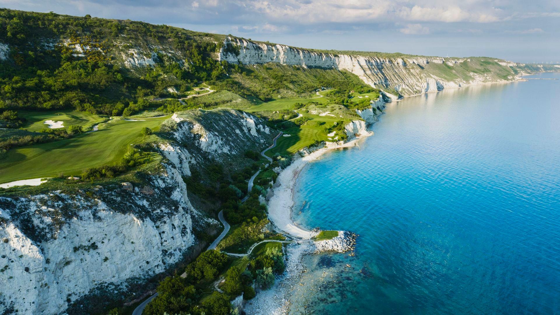 A straight wide fairway running along the coast on a mountainous landscape