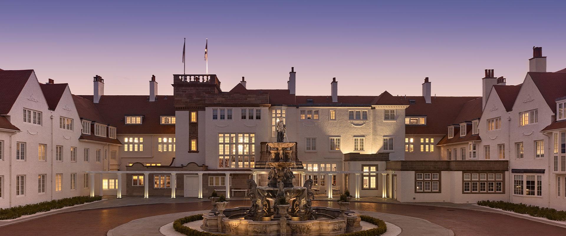 The resort illuminated at twilight, with its central fountain glowing in front.