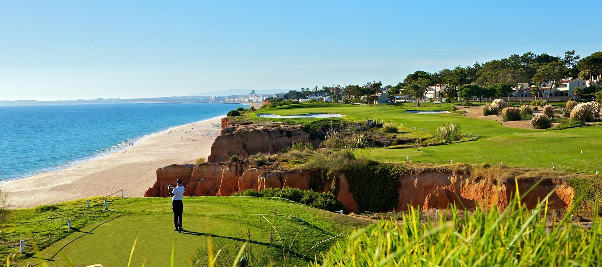 Player taking a tee shot on a long carry, cliffside Par 3
