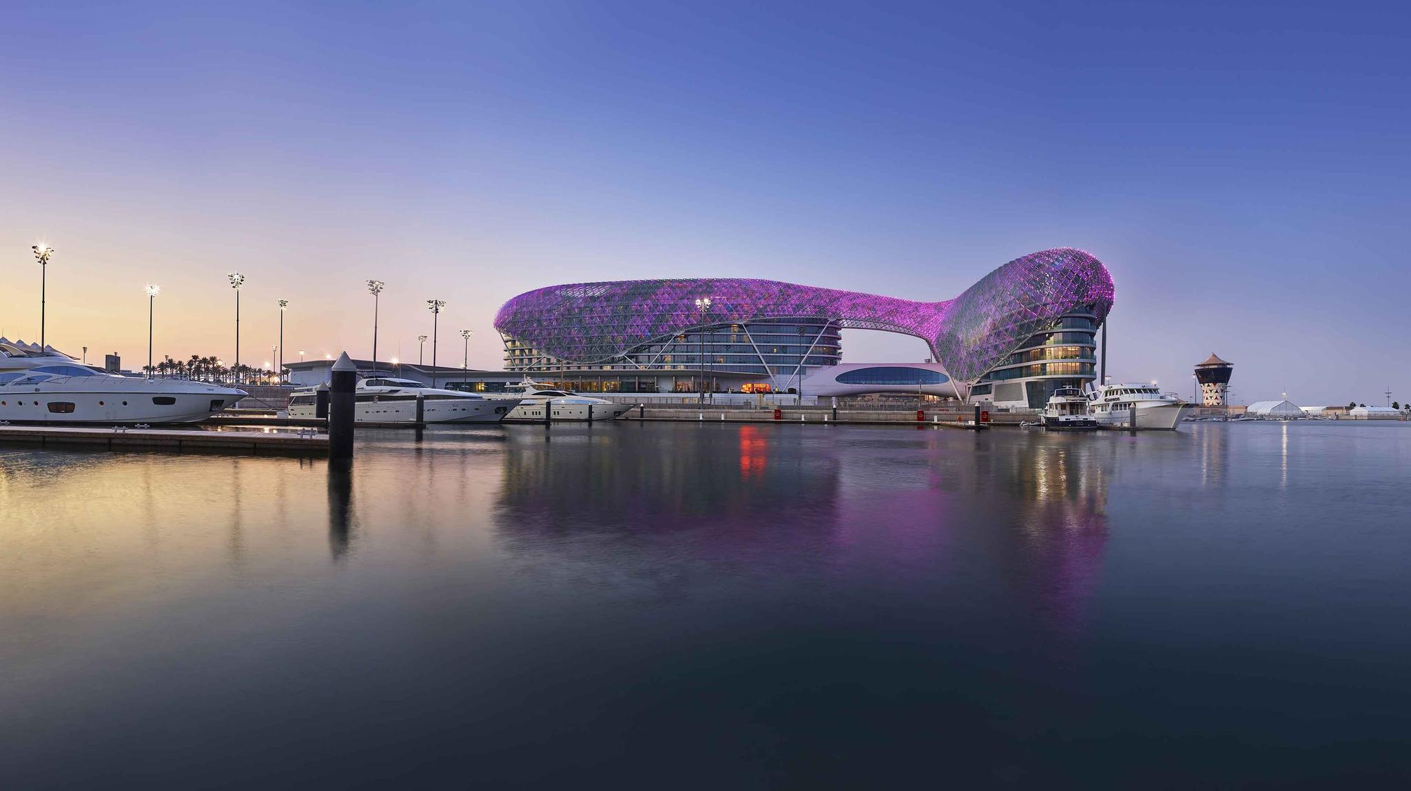 The W Abu Dhabi Yas Island hotel illuminated by purple light next to the dockyard