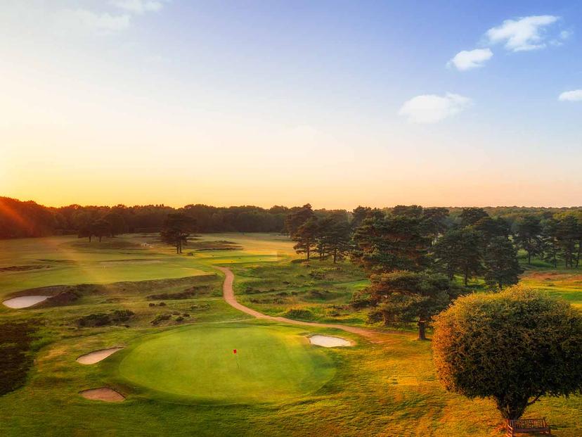 Golden sun setting over the well-maintained green at the Walton Heath Course