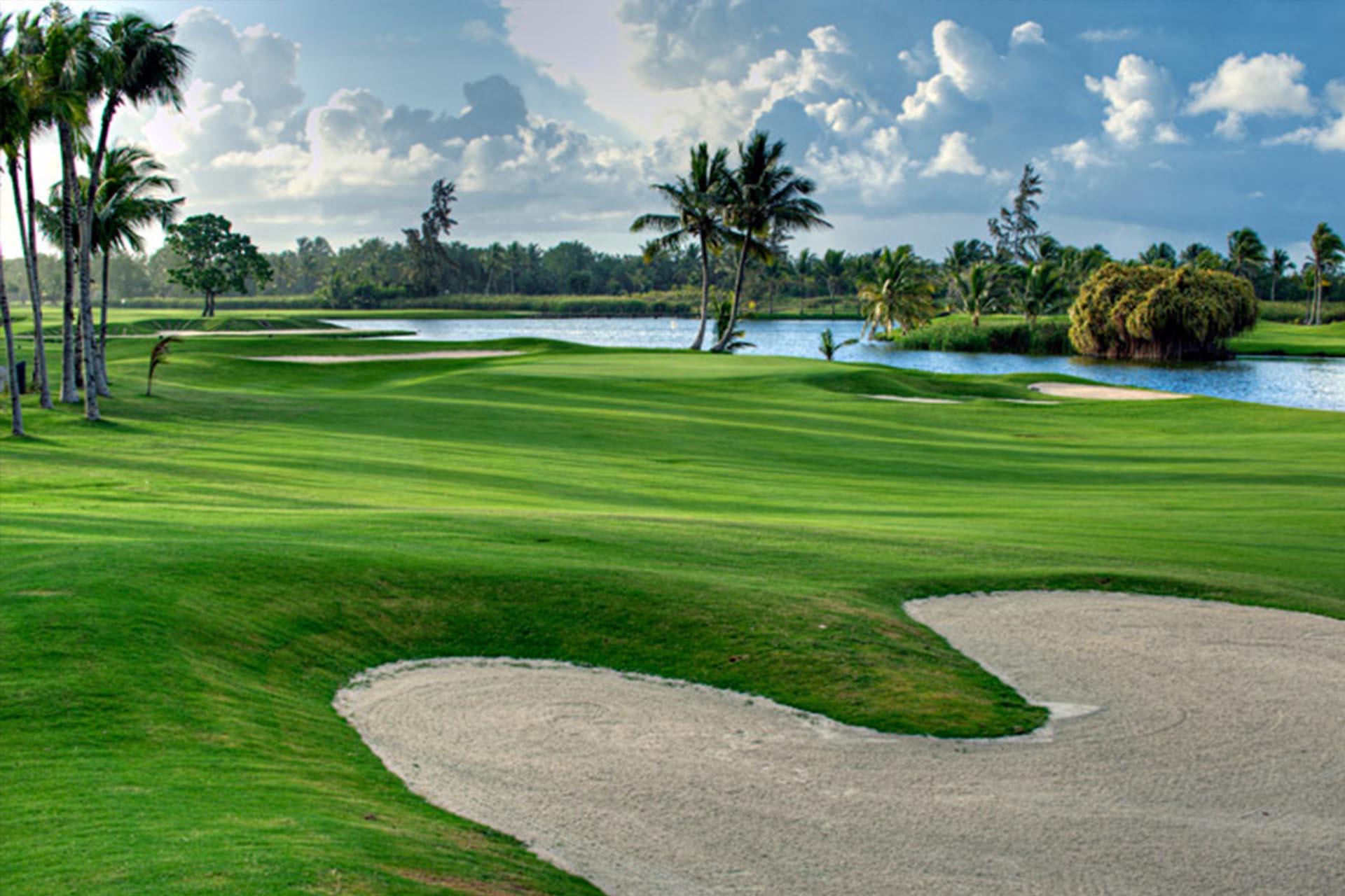 Sand bunkers littered on a wide fairway running along a water hazard