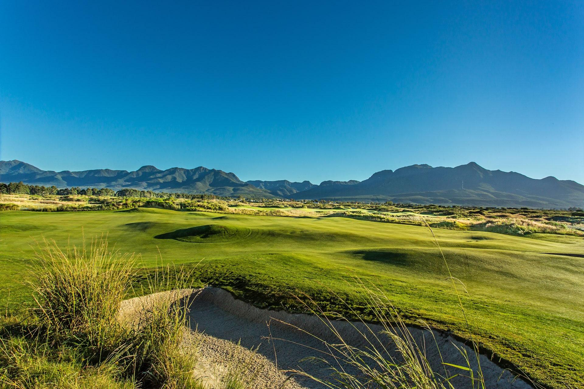 Wide view of the course at Fancourt Links with mountains in the background