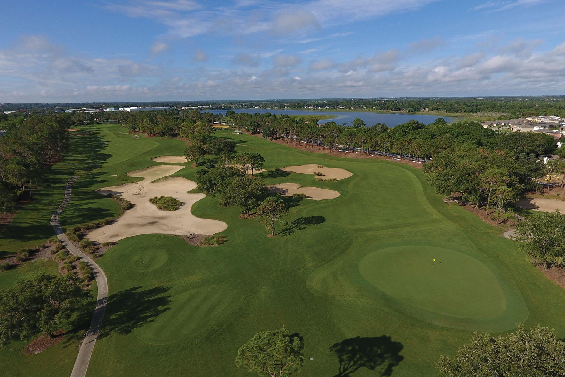 Birdseye view of a wide fairway littered with sand bunkers leading to a smooth green