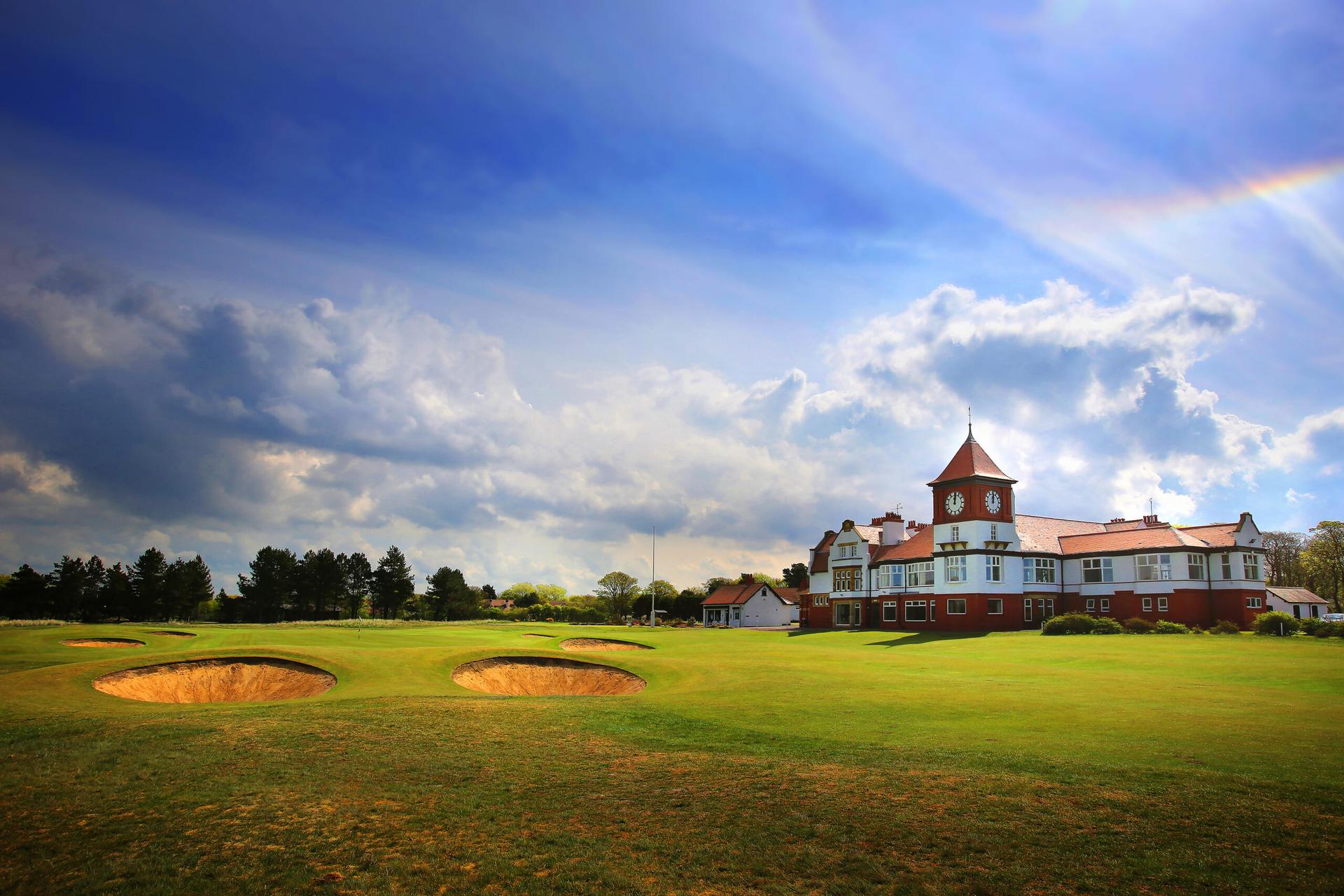 Panoramic view of a fairway nestled with sand bunkers with the clubhouse in the back