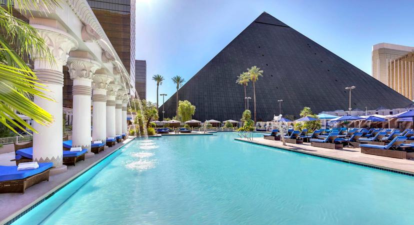 Panoramic view of an outdoor swimming pool at the resort lined with palm trees