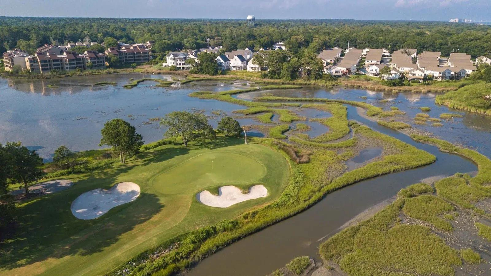 Overhead view of the manicured greens and winding fairways surrounded by water hazards at the golf club