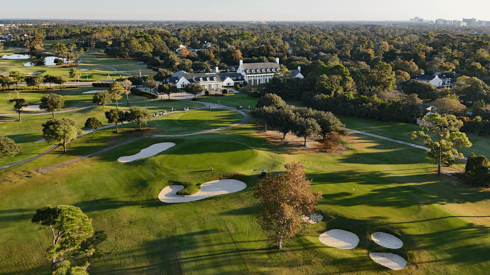 Aerial view of manicured fairways littered with sand bunkers with the resort clubhouse in the distance