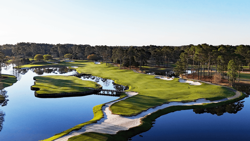 Overhead view of a wide fairway surrounded by a water hazard and a bridge to navigate the course