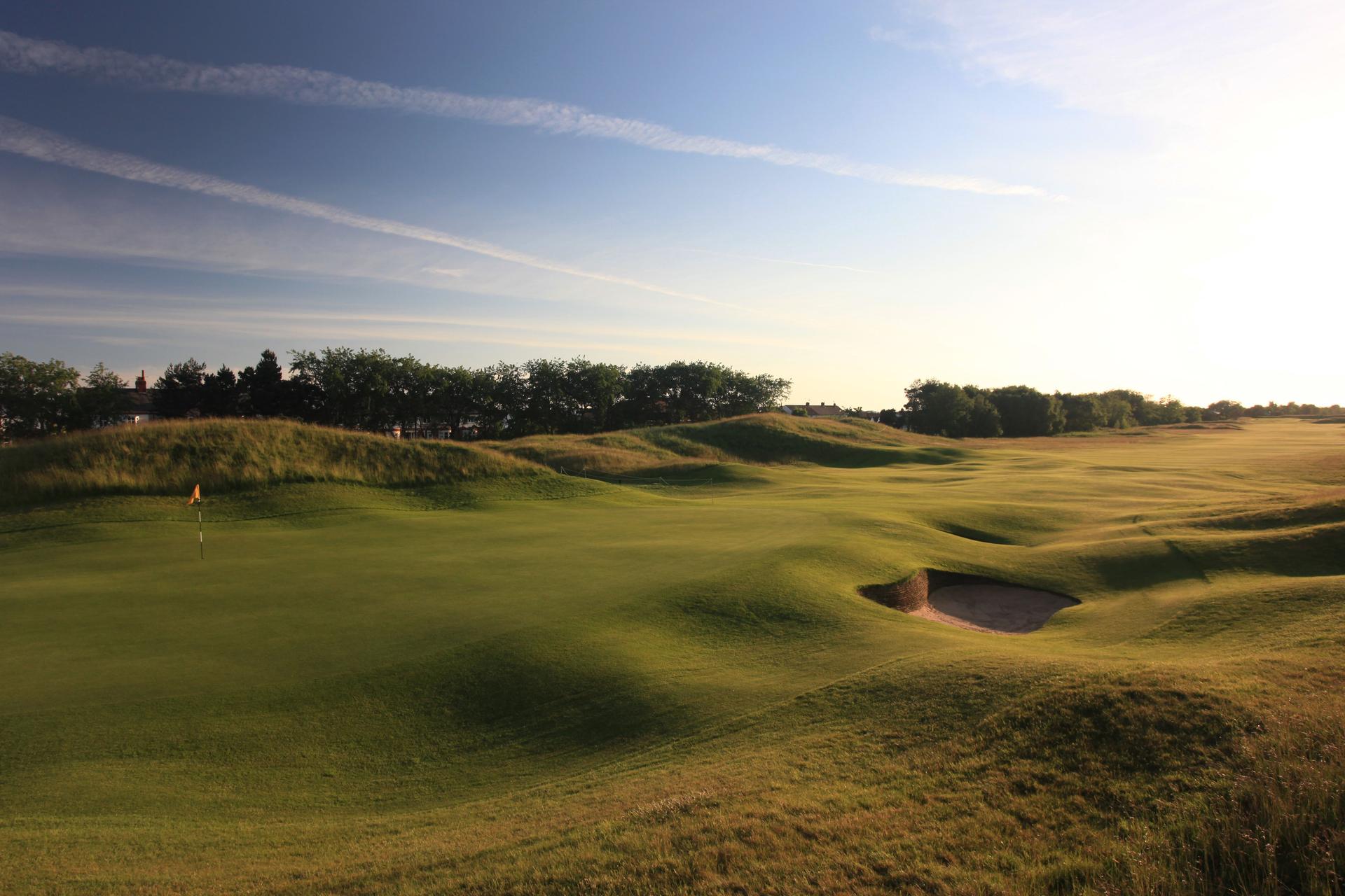 Panoramic view of a well maintained fairway leading to a smooth green at sun set