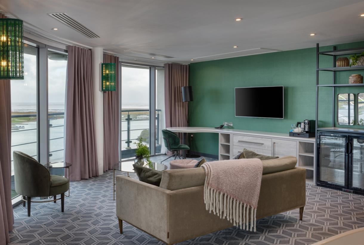 Living room as part of the penthouse sweet at the hotel with a panoramic window and balcony views of the water