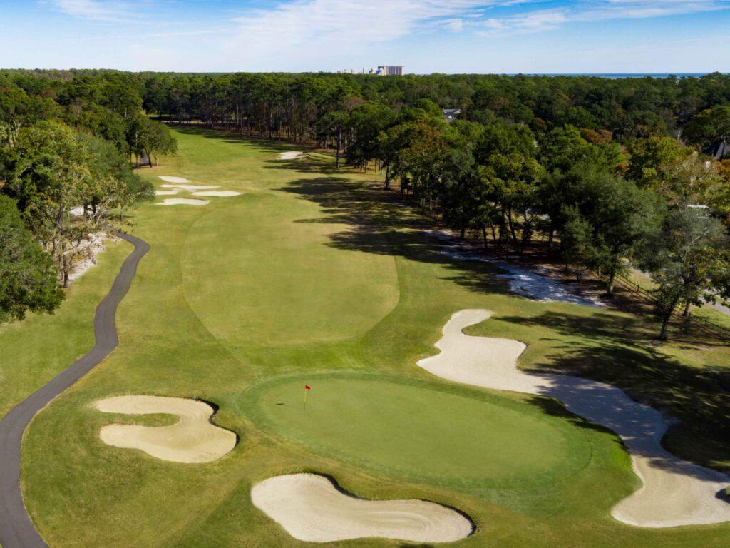 A wide fairway nestled with sand bunkers leading to a smooth green