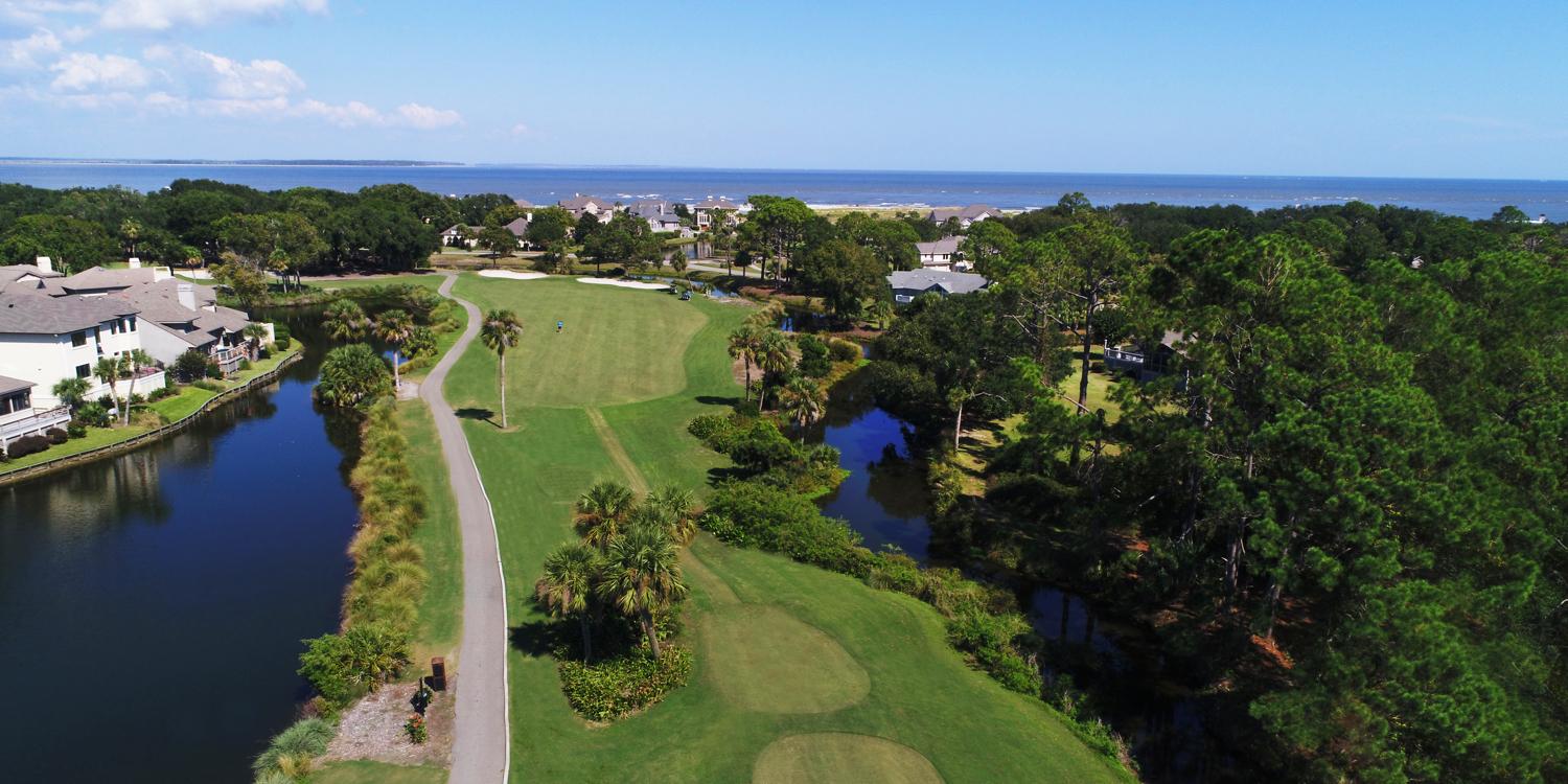A coastal golf course with homes and ocean views in the distance.