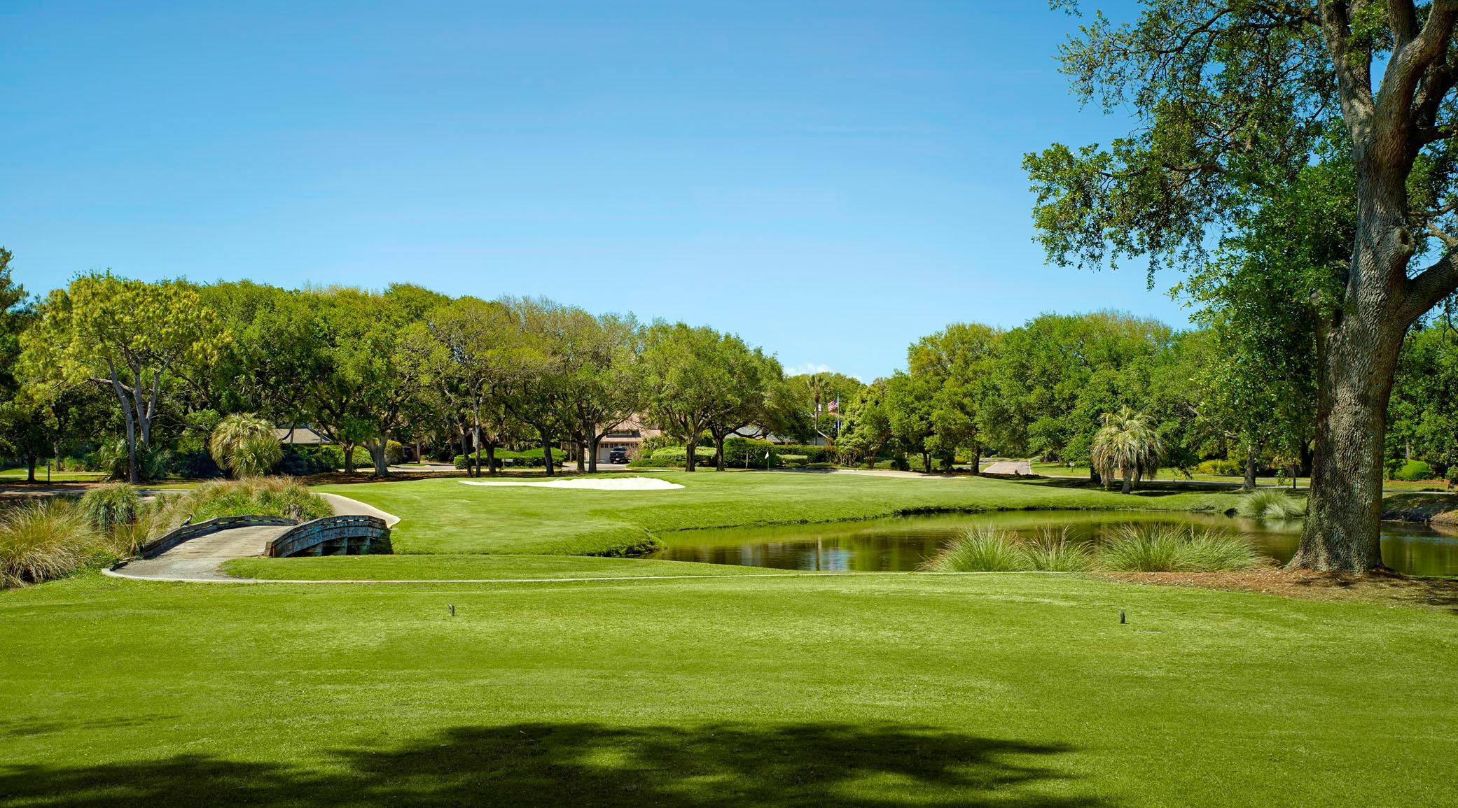 A fairway crosses a small stone bridge over a water feature.