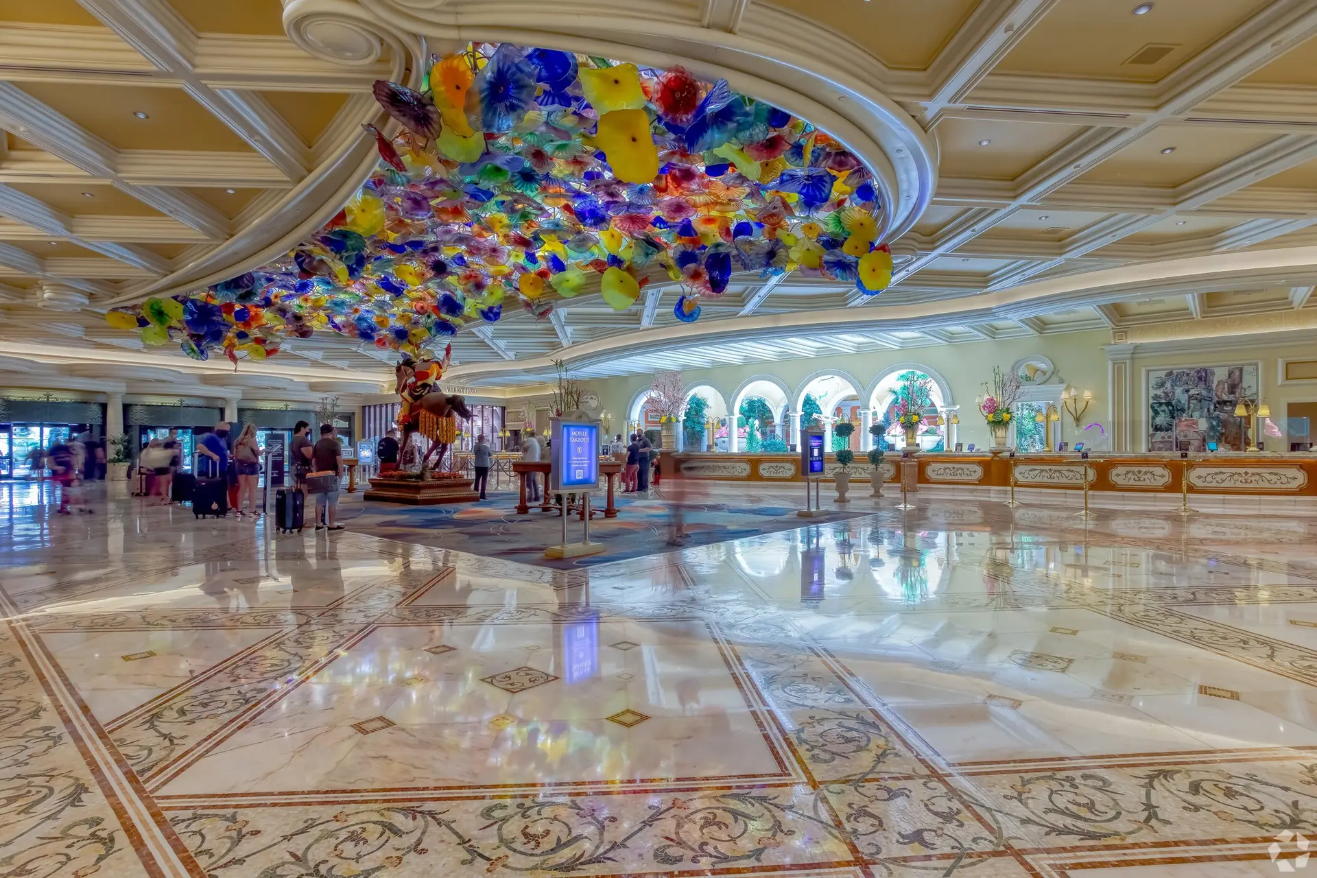 Elegant hotel lobby with a colorful glass ceiling installation.
