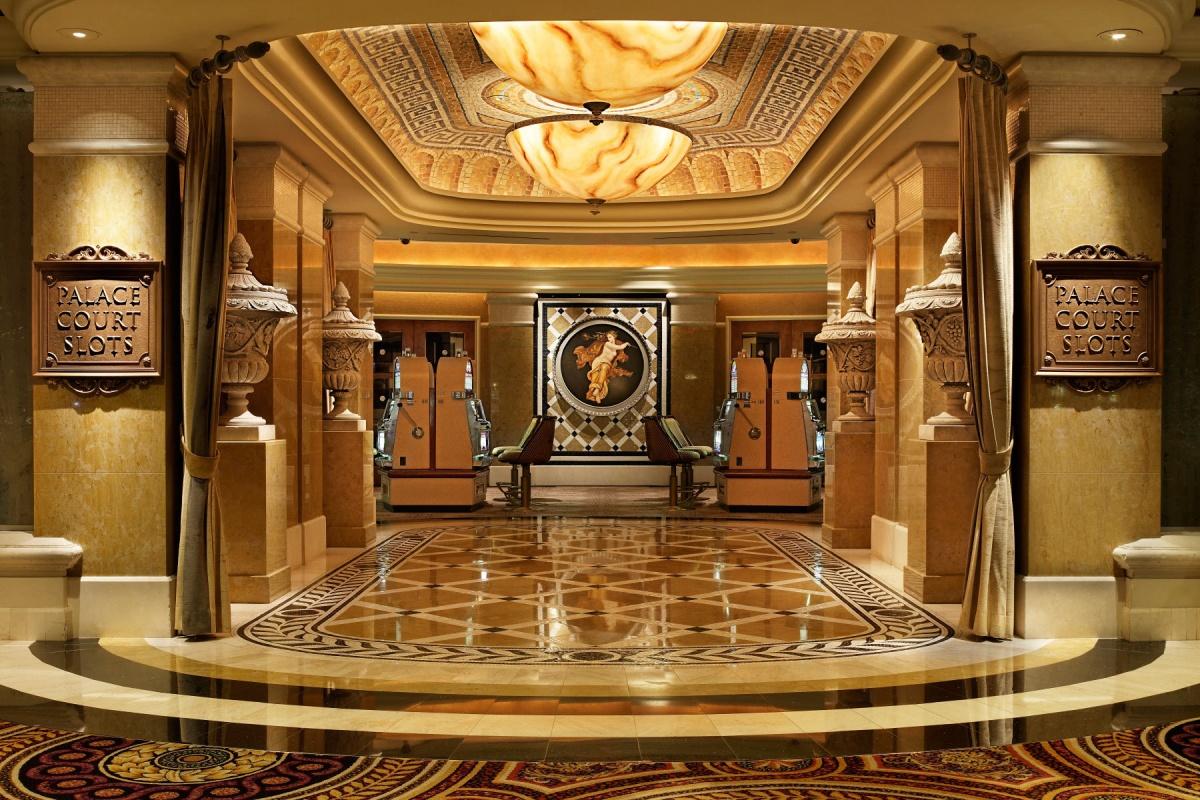 Luxurious casino entrance with slot machines and ornate decor.