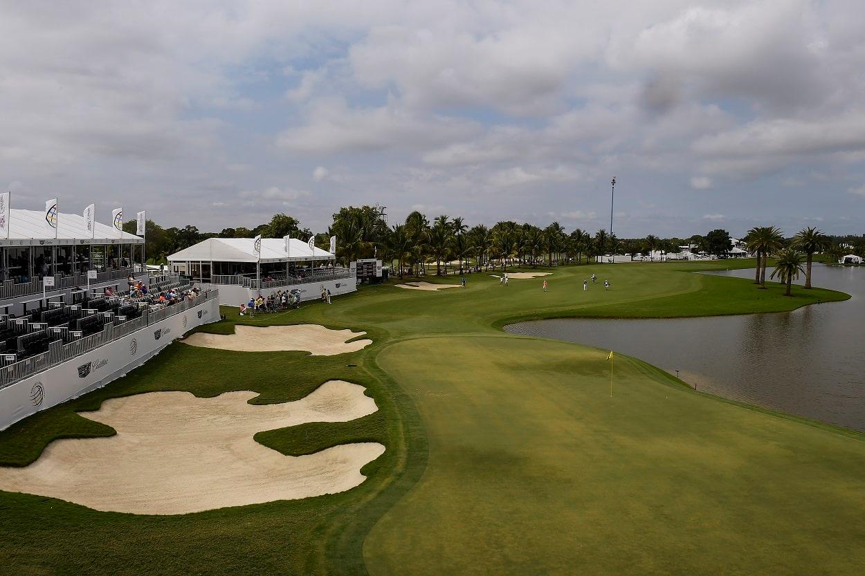 A tournament setting with grandstands overlooking a challenging green surrounded by water and sand traps.