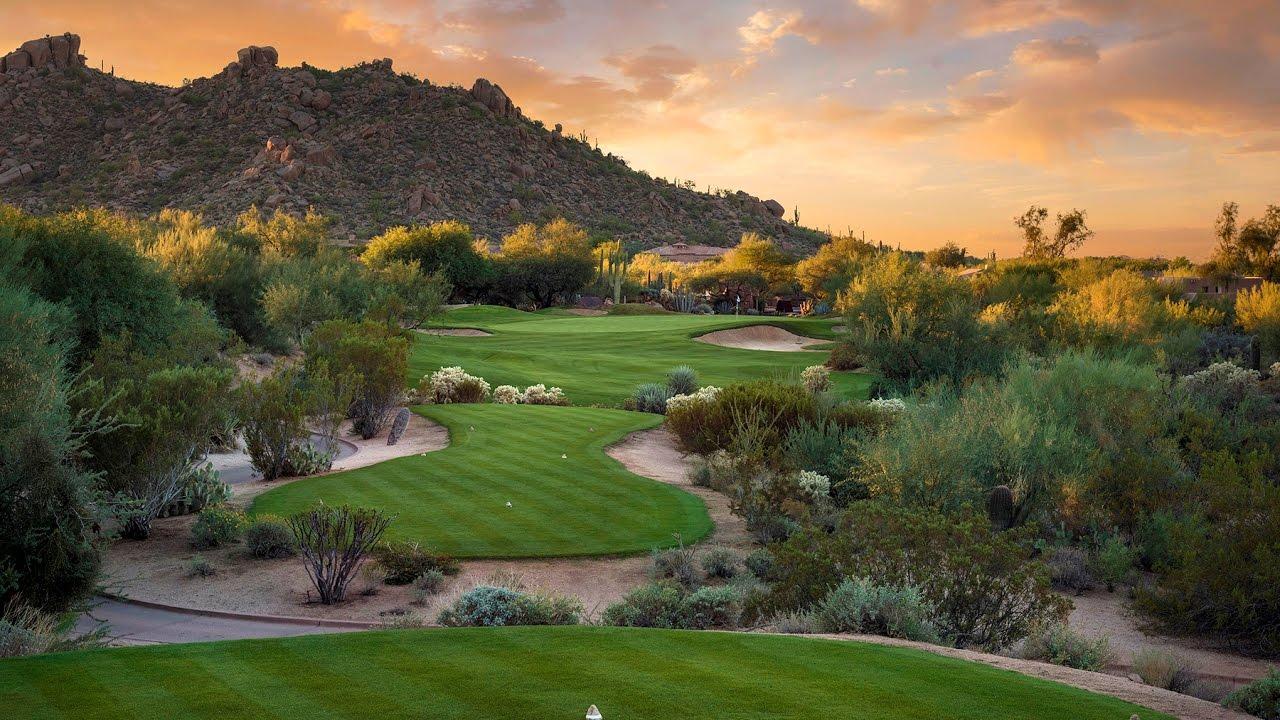 Rocky mountain towering over a green surrounded by sand bunkers