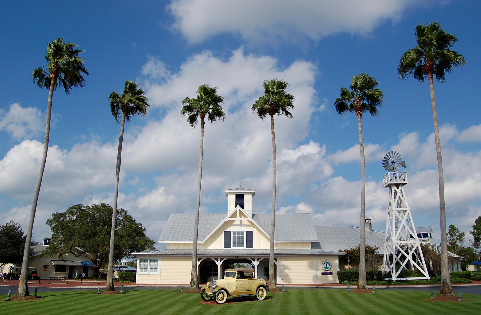 Palm trees surround a historic car placed as art work in front of the clubhouse