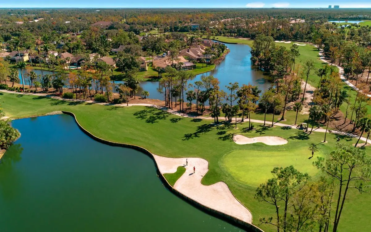 Golfers standing in a sand bunker on the course next to the green with local villas in the distance