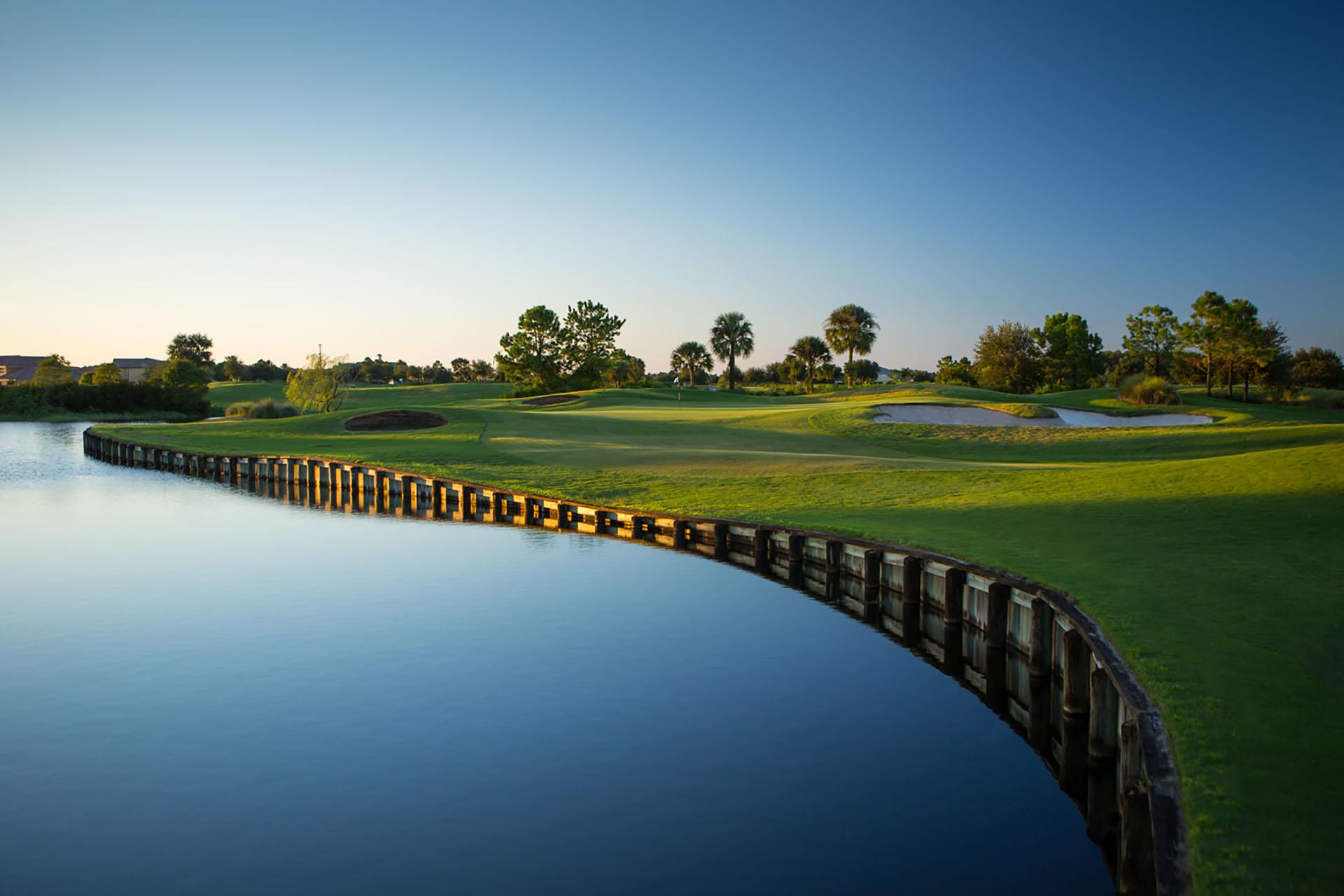 Winding fairway and deep bunkers elevated from the water hazard with a bamboo wall