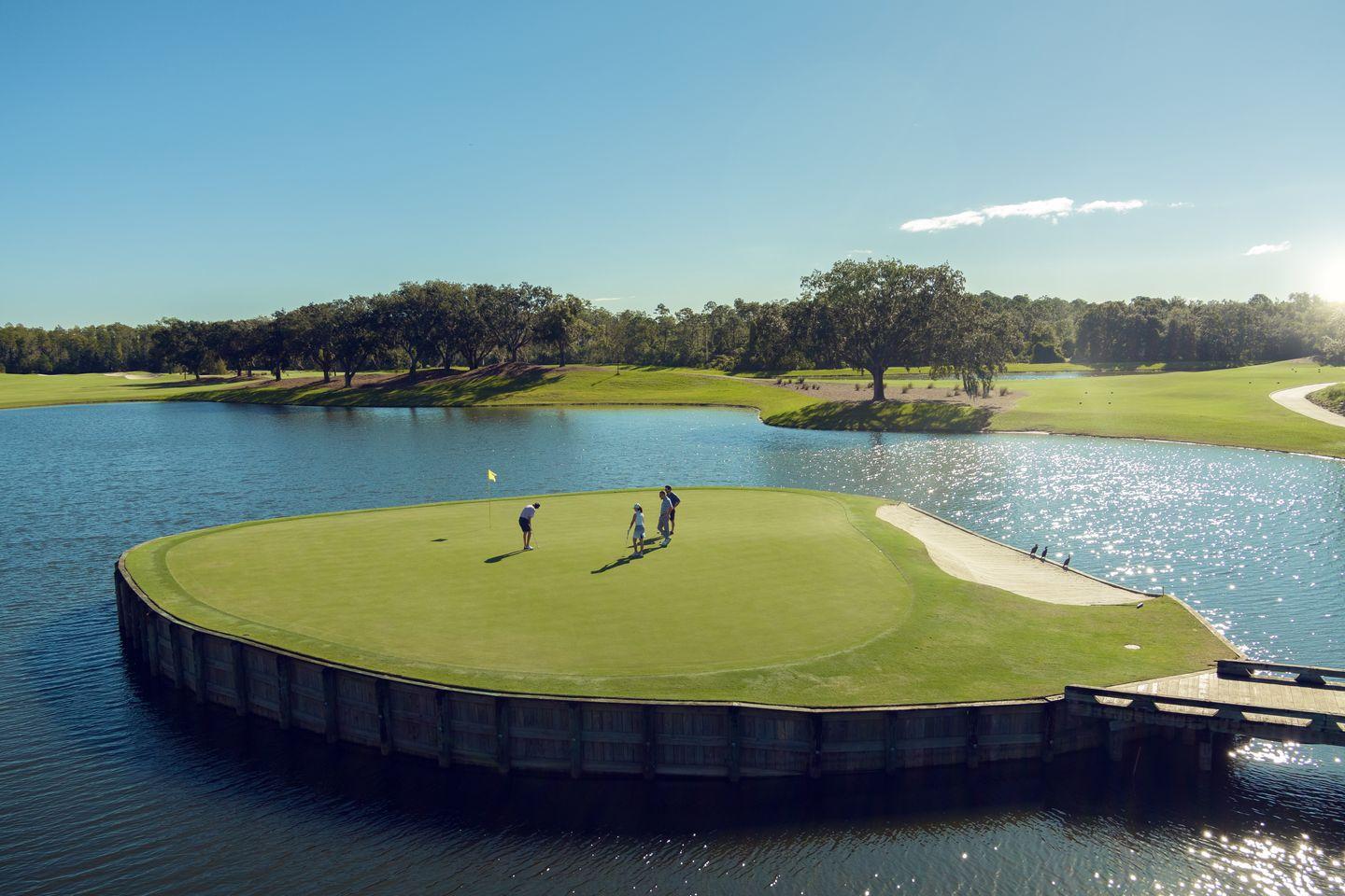 Golfers putt on a unique island green surrounded by sparkling water.