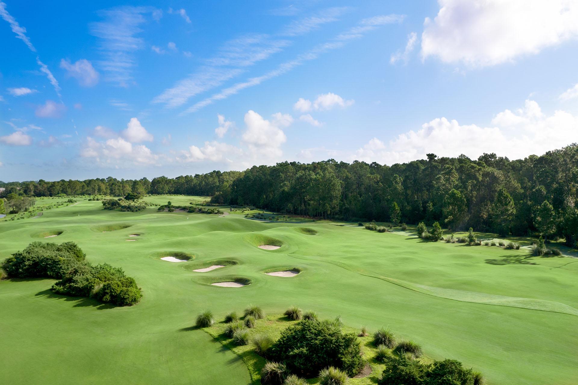 Panoramic view of the course with well maintained fairways scattered with bunkers under blue skies