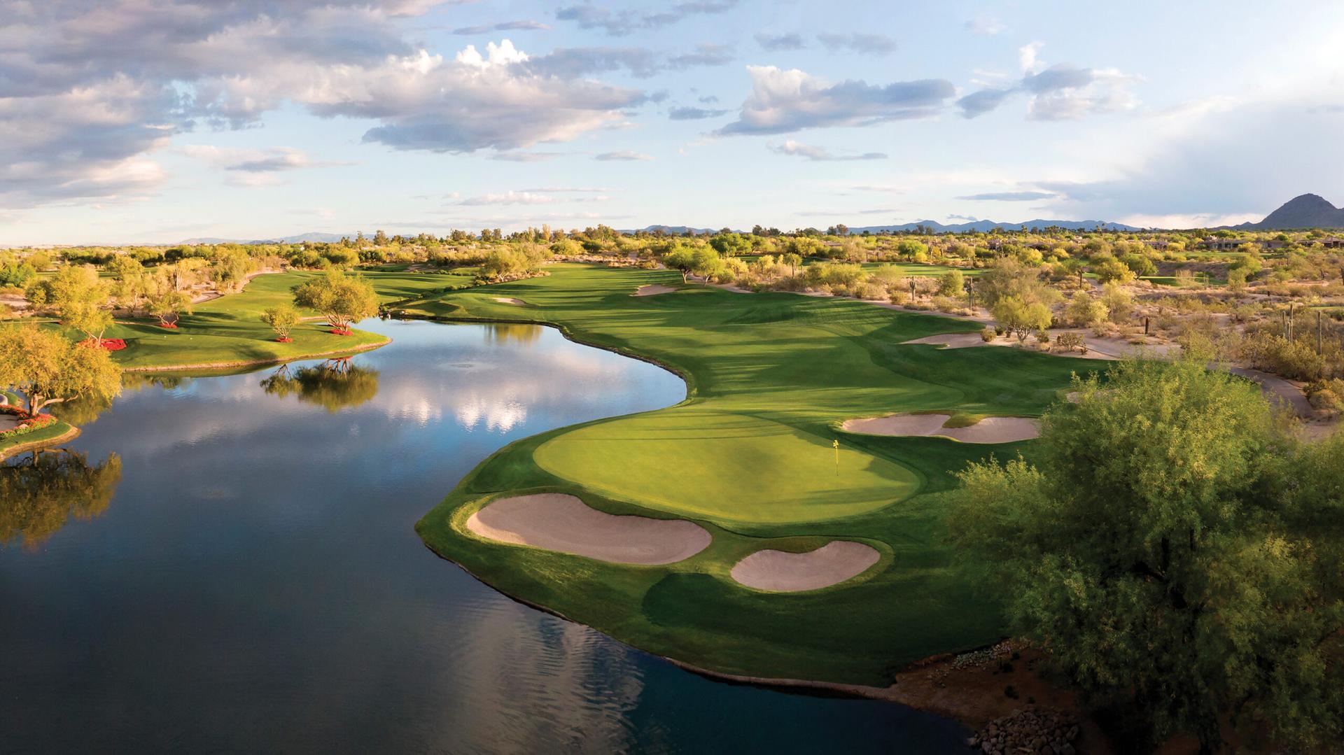Overhead shot of a green surrounded by sand bunkers placed next to a water hazard