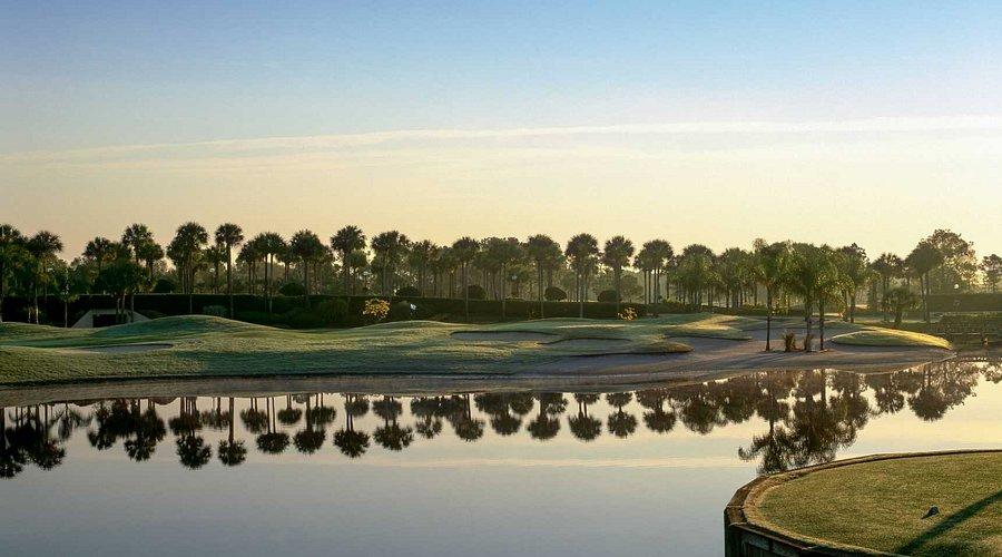 Sun setting over the Hawk,s Landing Gold course causing the water hazard to reflect the palm trees