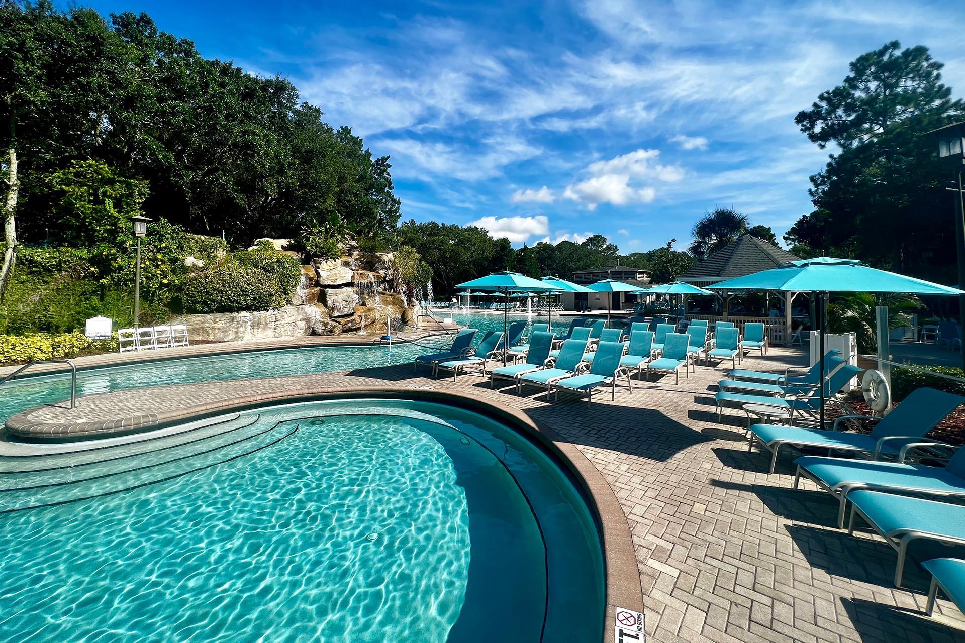 Multiple sun beds at the course next to the clear blue pool.