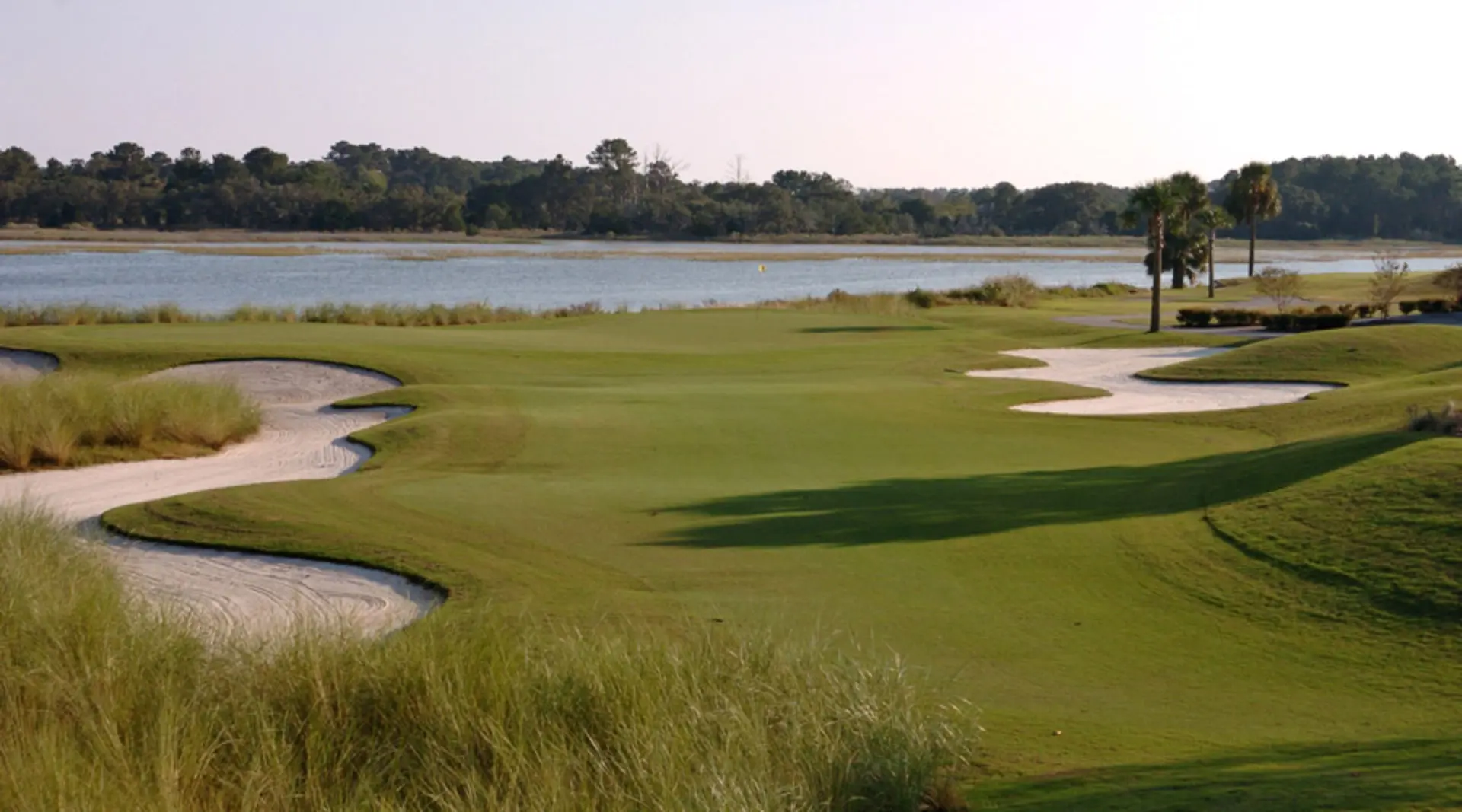 Large uniquely shaped sand bunkers at the Oak Point course surrounding a well-kept green