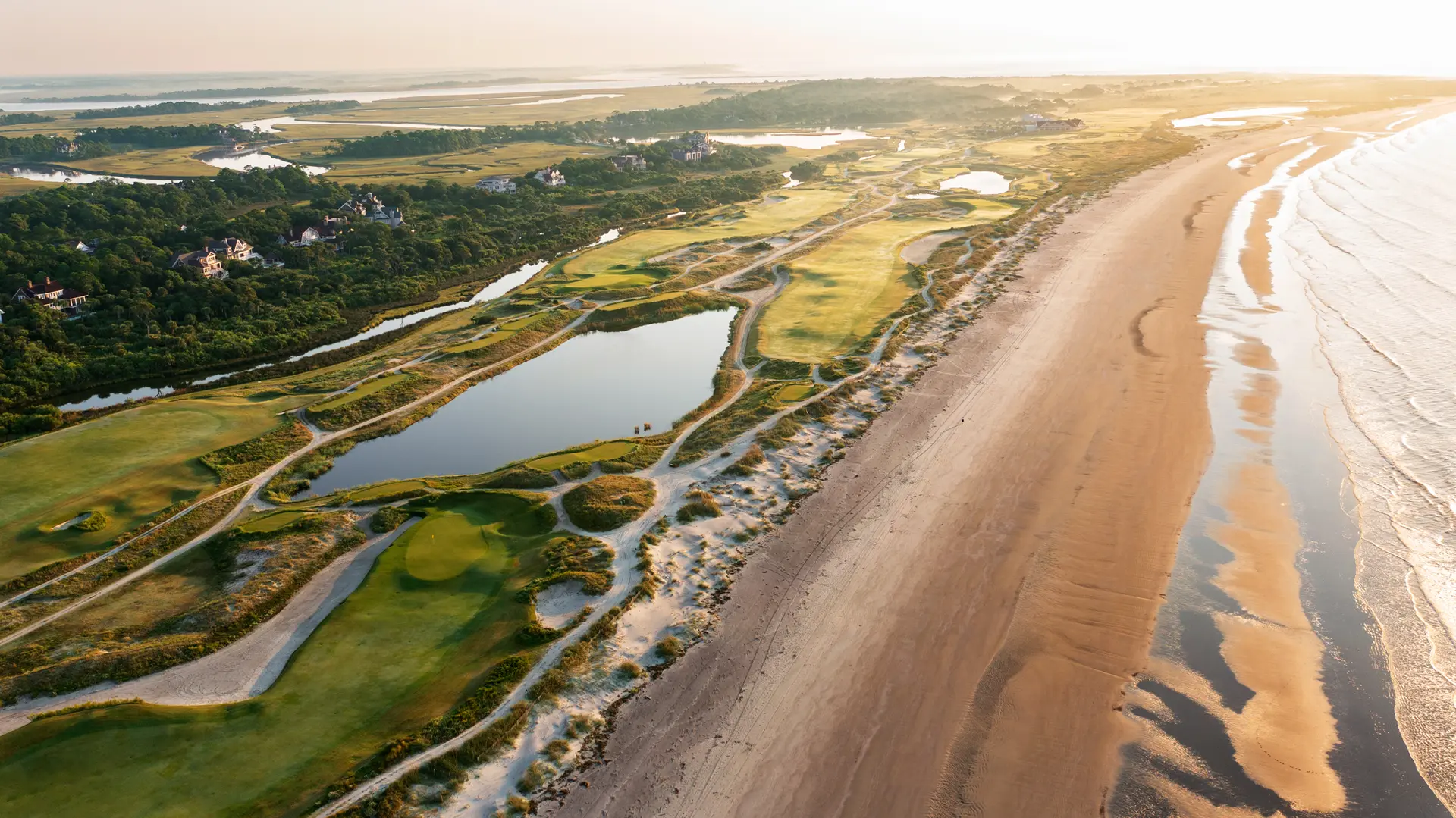 An aerial view of the ocean course, featuring lush greens and winding waterways by the beach.
