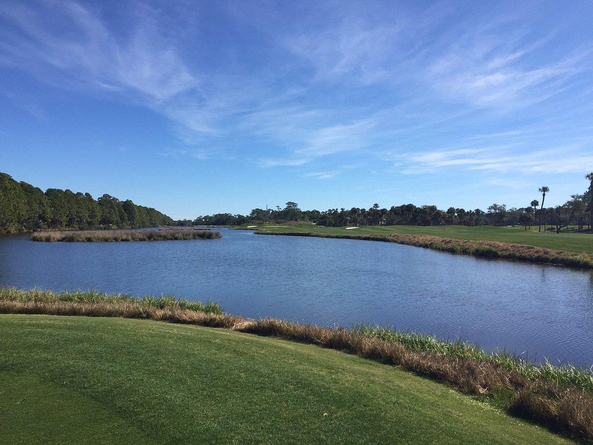 Serene waterway view with golf greens along the edges.