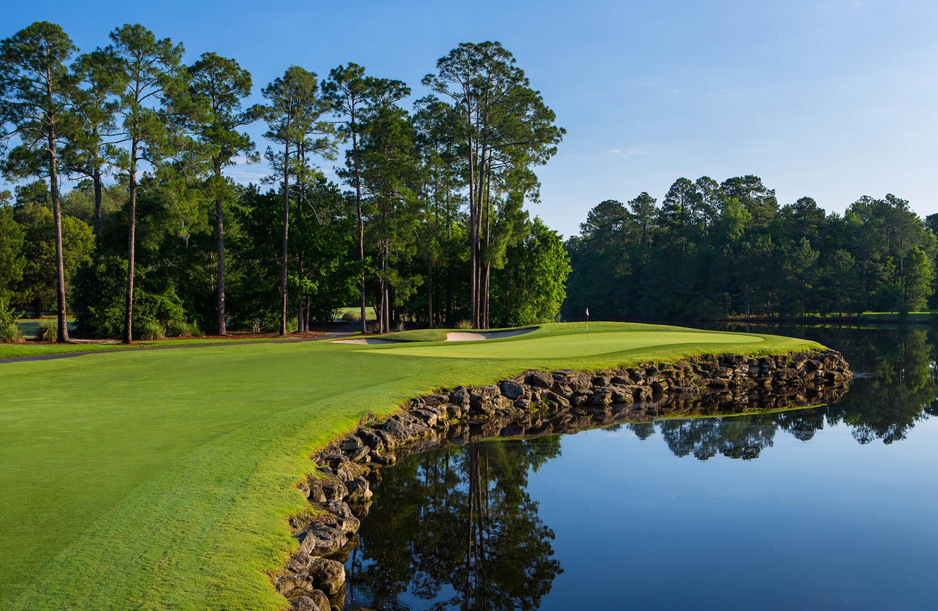 Stone wall elevating the green from a large water hazard at the King & Bear Course