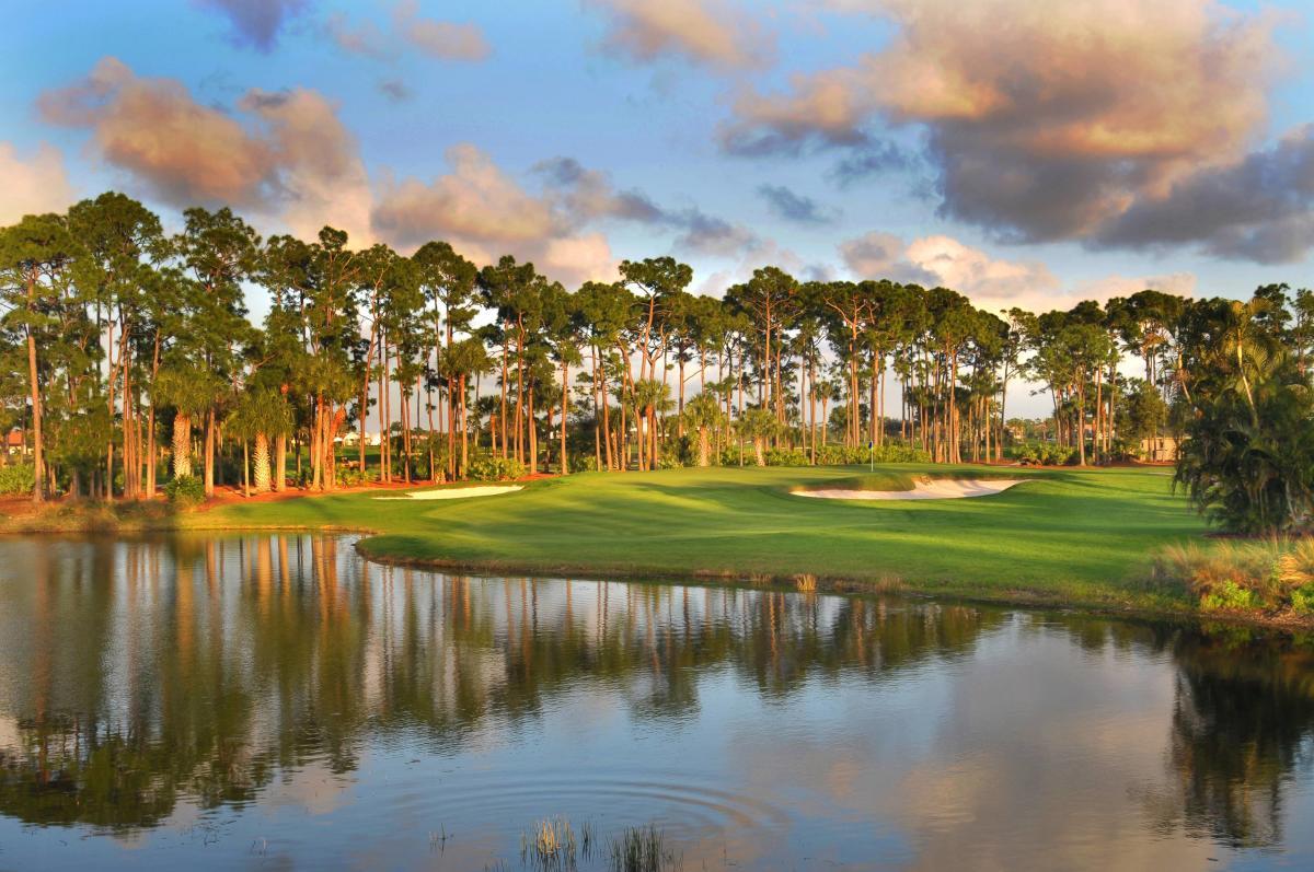 Green surrounded by sand bunkers, tall trees and large water hazard at the National course
